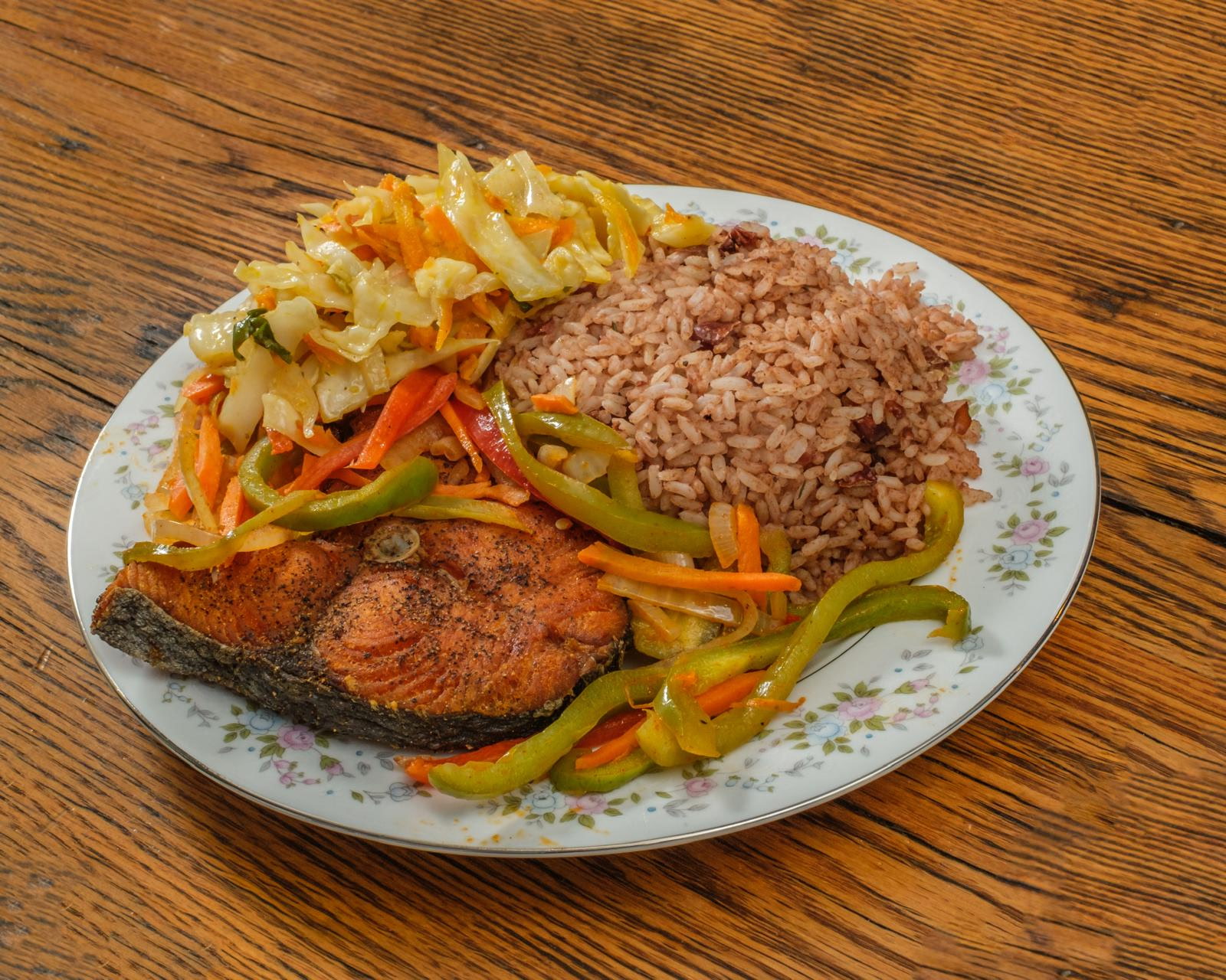 Fried salmon steak with cabbage and rice and peas